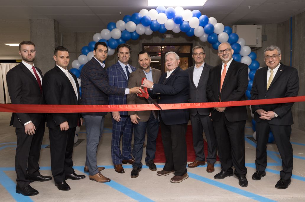 Nine men in suits standing for grand opening ribbon cutting