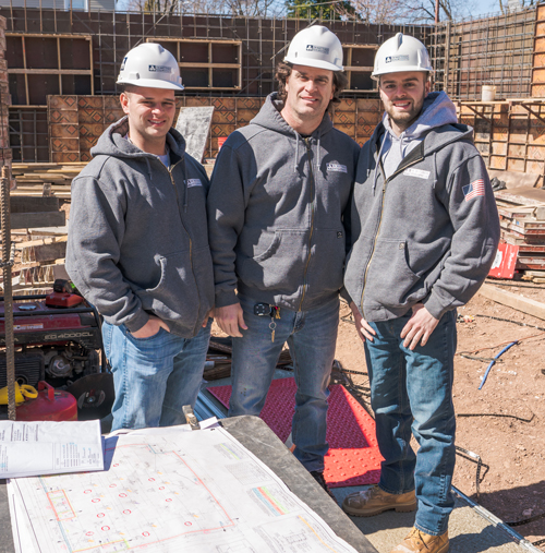 Three people standing in construction site