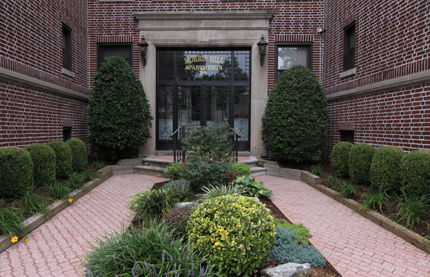 Close-up front entrance of Morris-Hill Apartments with trees and shrubs